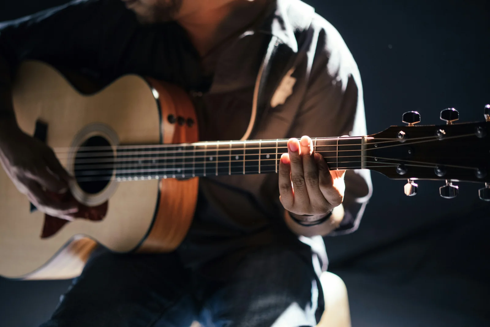 Mãos tocando violão em luz baixa